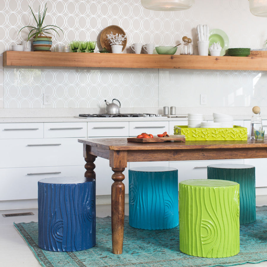 stump stools in a variety of greens and blues around a kitchen table